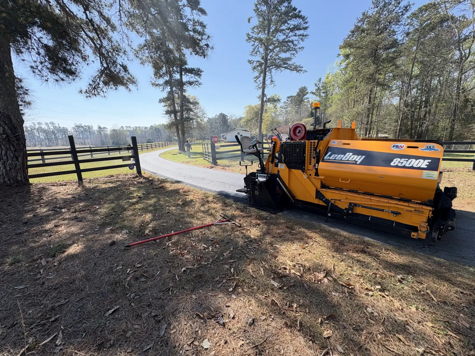 LeeBoy 8500E paver laying fresh hot-mix asphalt on a tree-lined driveway